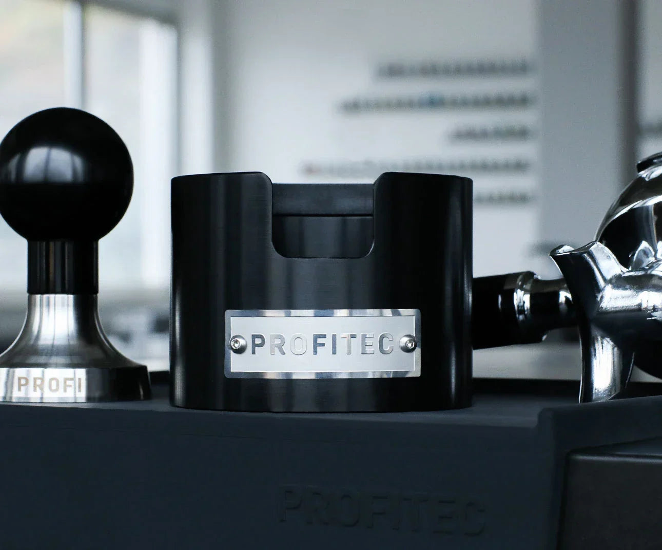 Profitec Tamperstation in black anodized aluminum with tamper and portafilter.